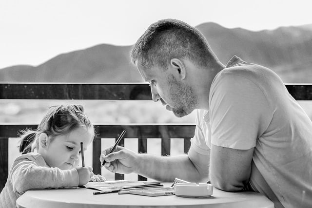 משמורת משותפת- אילוסטרציה של אב יושב עם ביתו ועוזר לה להכין שיעורי בית